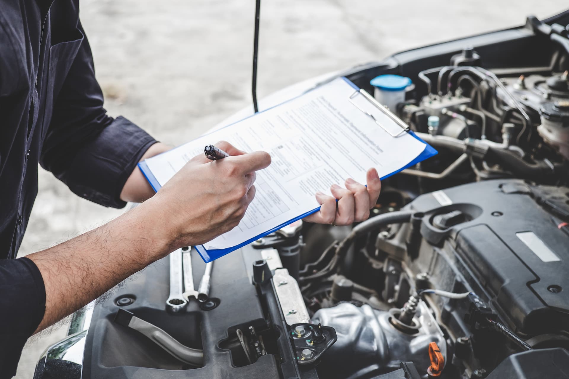 a man carrying out car servicing with a checklist